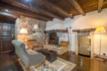 Rustic living room with stone walls, wooden beams, and a cozy fireplace.