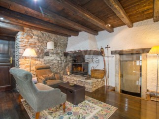 Rustic living room with stone walls, wooden beams, and a cozy fireplace.