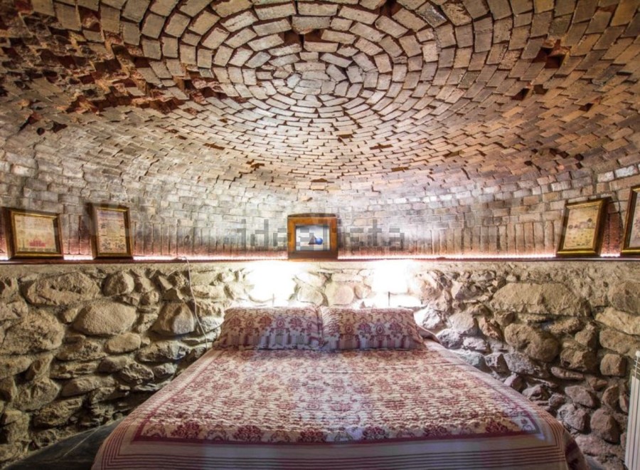 Unique cave-like bedroom with a stunning brick dome ceiling and stone walls.