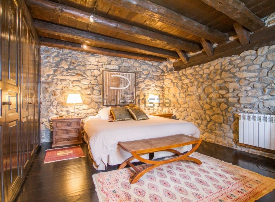Rustic bedroom with exposed wooden beams and stone walls.