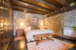Rustic bedroom with exposed wooden beams and stone walls.