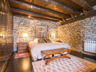 Rustic bedroom with exposed wooden beams and stone walls.