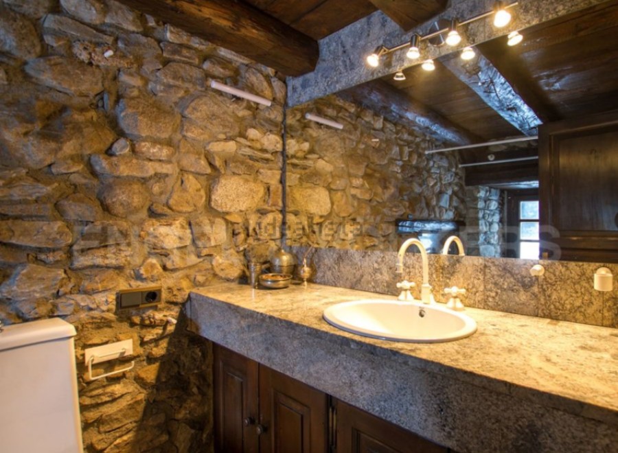 Rustic bathroom with stone walls and granite countertop.
