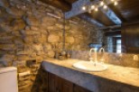 Rustic bathroom with stone walls and granite countertop.
