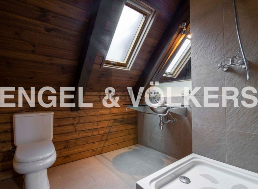 Charming attic bathroom with wooden walls, skylights, and modern fixtures.
