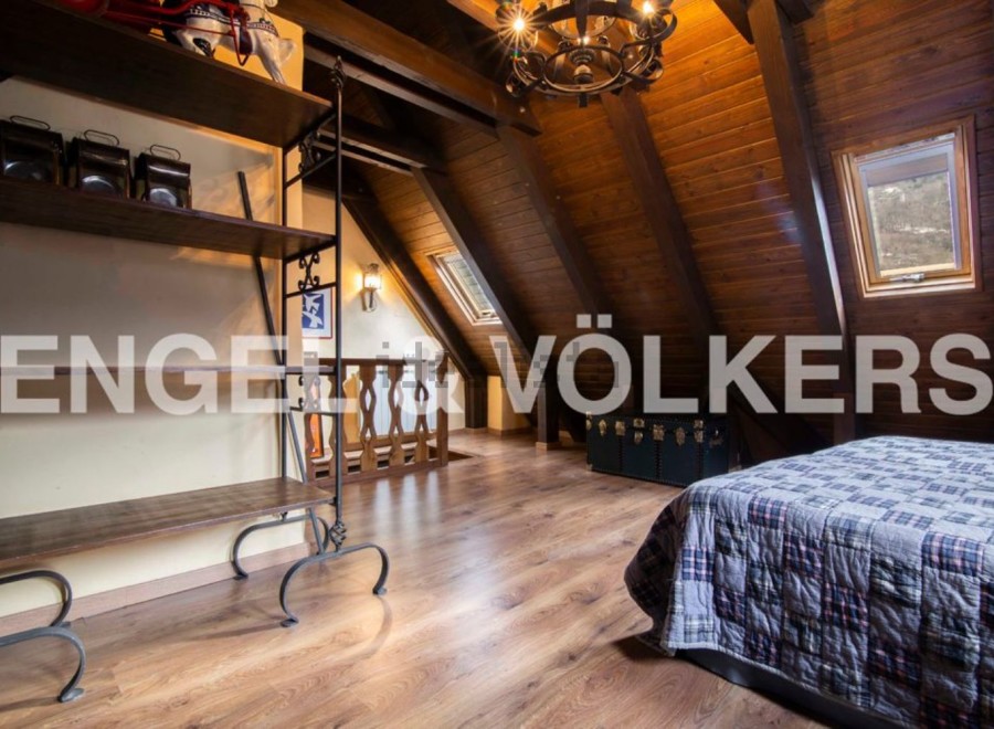 Charming attic bedroom with wooden beams, skylights, and a cozy atmosphere.