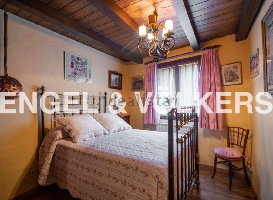 Charming bedroom with antique brass bed, wooden beams, and quaint decor.