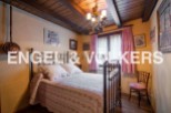 Charming bedroom with antique brass bed, wooden beams, and quaint decor.