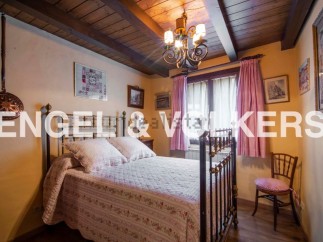 Charming bedroom with antique brass bed, wooden beams, and quaint decor.
