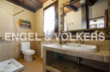 Rustic bathroom with tiled walls and floors, featuring a toilet, shower, and ornate sink vanity.