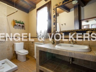 Rustic bathroom with tiled walls and floors, featuring a toilet, shower, and ornate sink vanity.