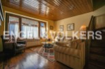Cozy living room with wooden floors and beamed ceiling, featuring a large bay window and comfortable seating.