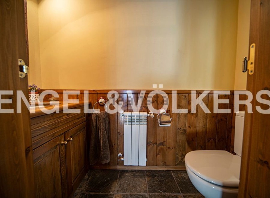 Charming rustic bathroom with wooden paneling, a built-in vanity, and a toilet.