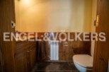 Charming rustic bathroom with wooden paneling, a built-in vanity, and a toilet.