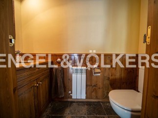Charming rustic bathroom with wooden paneling, a built-in vanity, and a toilet.