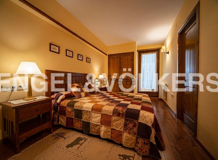 Cozy bedroom with a patchwork quilt and wooden furniture.
