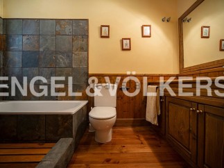 This charming bathroom boasts a rustic-chic design with slate tile, wooden cabinetry, and hardwood floors.