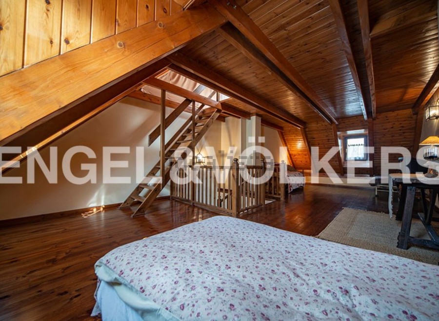 Discover this charming attic bedroom with wooden beams and flooring, offering a cozy and rustic atmosphere.