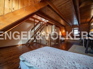 Discover this charming attic bedroom with wooden beams and flooring, offering a cozy and rustic atmosphere.
