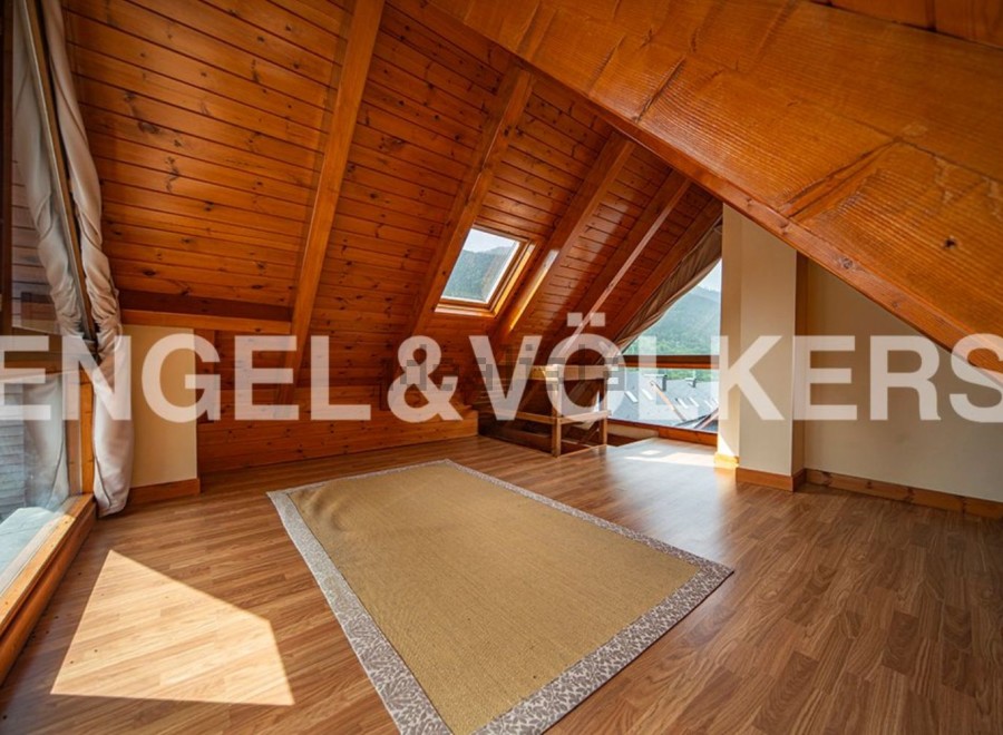 This attic room boasts a stunning wooden ceiling and large windows offering breathtaking mountain views.