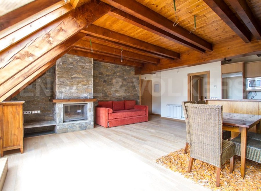 This stunning attic apartment boasts a spacious open-plan living area with exposed wooden beams and a cozy fireplace.