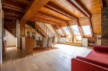 This stunning chalet boasts a spacious open-plan living area with exposed wooden beams and large skylights, creating a bright and airy atmosphere.