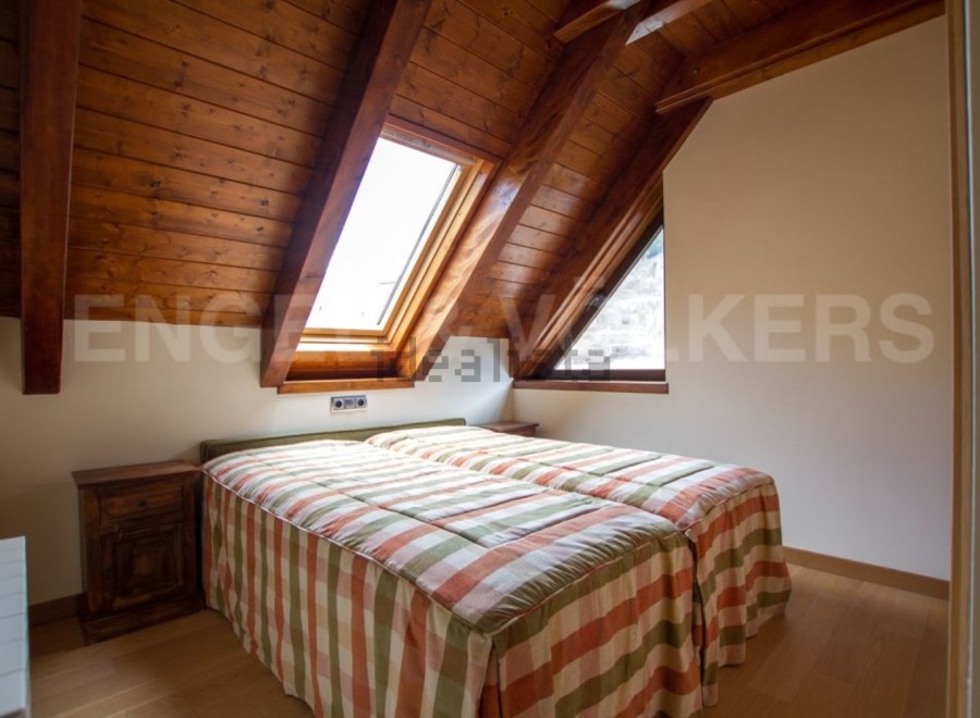 Cosy attic bedroom with wooden beams and skylights.