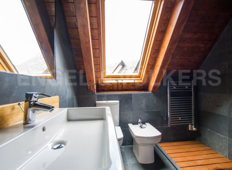 This stunning bathroom boasts a unique sloped ceiling with skylights, creating a bright and airy atmosphere.