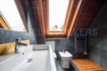 This stunning bathroom boasts a unique sloped ceiling with skylights, creating a bright and airy atmosphere.