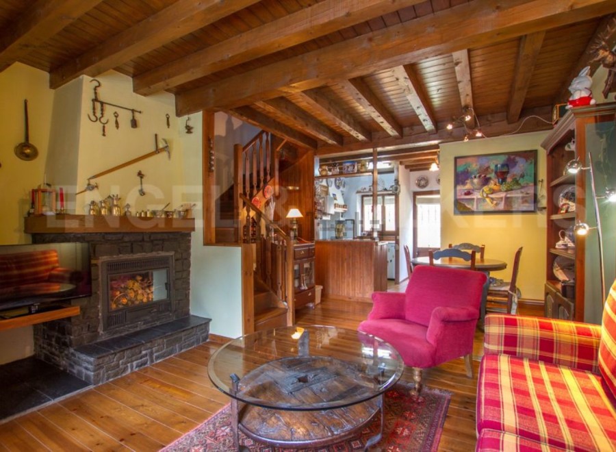 Charming rustic living room with exposed wooden beams, a cozy fireplace, and ample natural light.