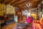 Charming rustic living room with exposed wooden beams, a cozy fireplace, and ample natural light.