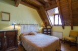 Charming attic bedroom with wooden beams, offering a cozy and rustic atmosphere.