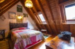 Charming attic bedroom with wooden beams, skylights, and patchwork quilt.
