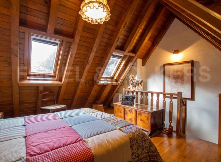 Charming attic bedroom with wooden beams, skylights, and a patchwork quilt.