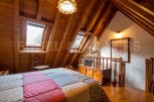 Charming attic bedroom with wooden beams, skylights, and a patchwork quilt.