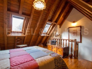 Charming attic bedroom with wooden beams, skylights, and a patchwork quilt.