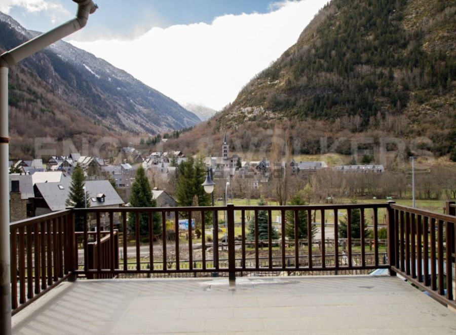 Mountain views from a balcony with wooden railings.