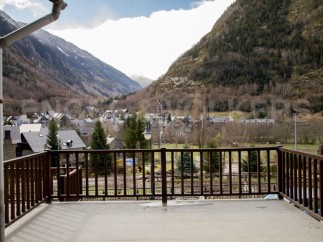 Mountain views from a balcony with wooden railings.