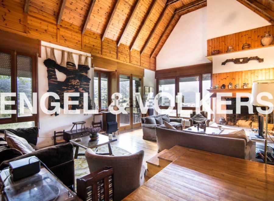 Rustic mountain chalet with high wooden ceilings and large windows offering scenic views.