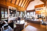 Rustic mountain chalet with high wooden ceilings and large windows offering scenic views.