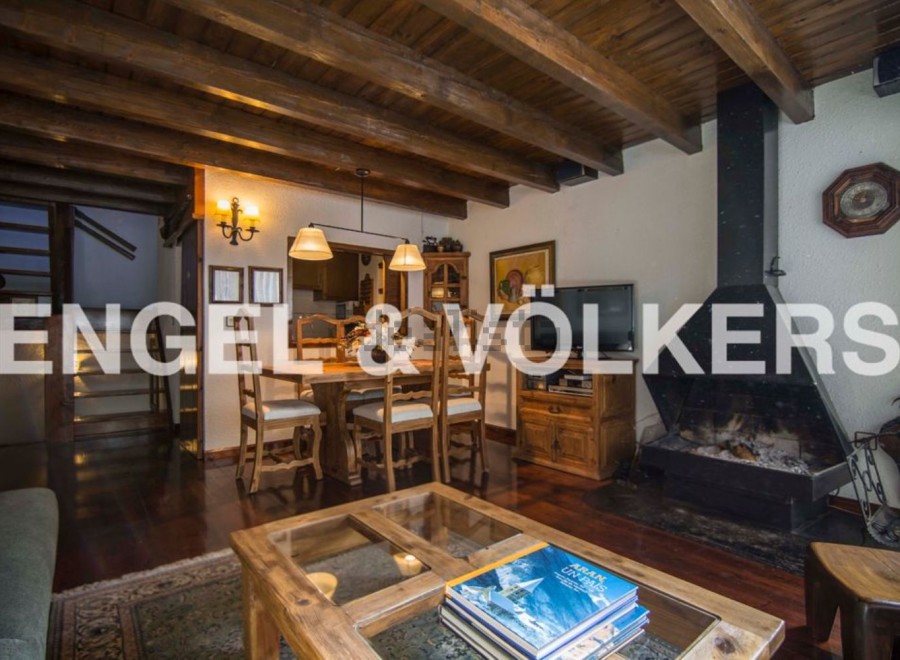 Charming chalet-style living room with exposed wooden beams, a cozy fireplace, and a spacious dining area.