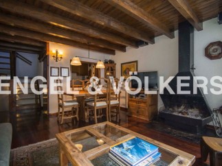 Charming chalet-style living room with exposed wooden beams, a cozy fireplace, and a spacious dining area.
