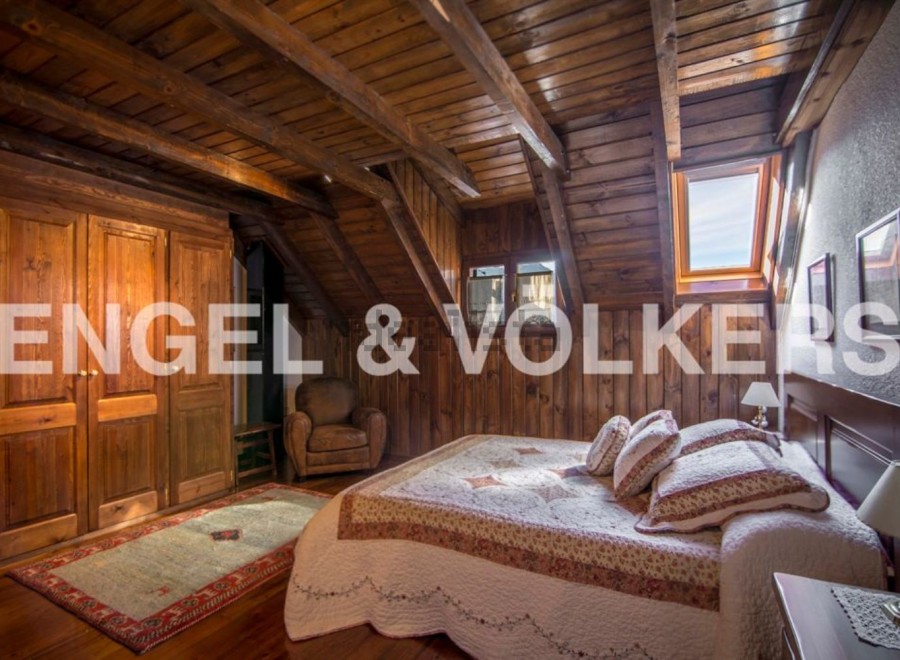 Charming rustic bedroom with wooden beams, skylights, and built-in wardrobe.