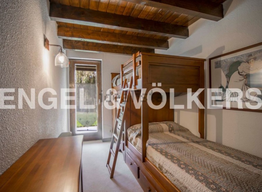 Charming bunk beds in a rustic-style bedroom with wooden beams and a tranquil garden view.