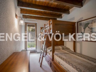 Charming bunk beds in a rustic-style bedroom with wooden beams and a tranquil garden view.