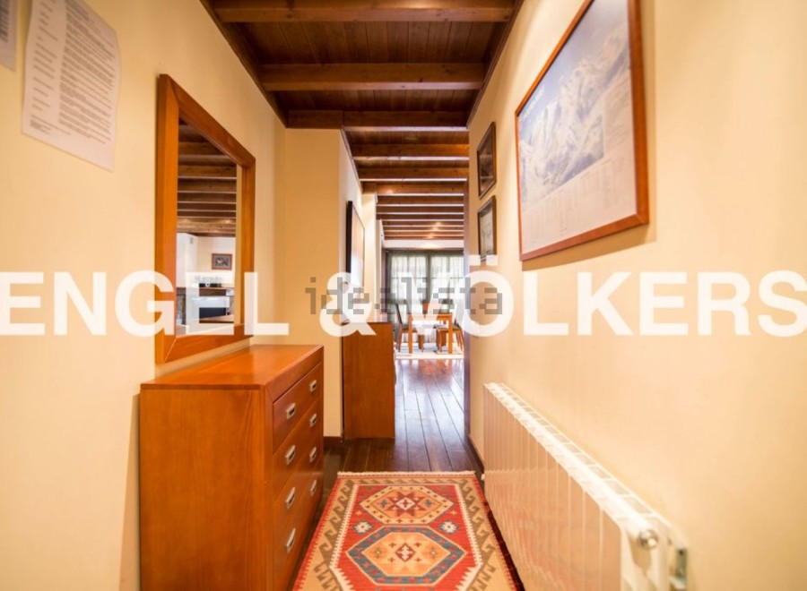 This charming hallway boasts a wooden dresser, a mirror reflecting the cozy interior, and a vibrant rug adding warmth to the wooden floor.