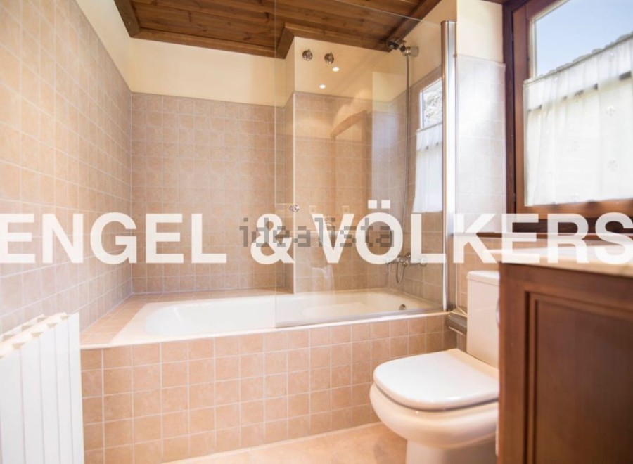 This charming bathroom boasts a classic design with beige tile, a built-in bathtub, and a separate toilet.