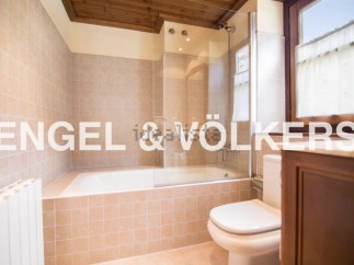 This charming bathroom boasts a classic design with beige tile, a built-in bathtub, and a separate toilet.