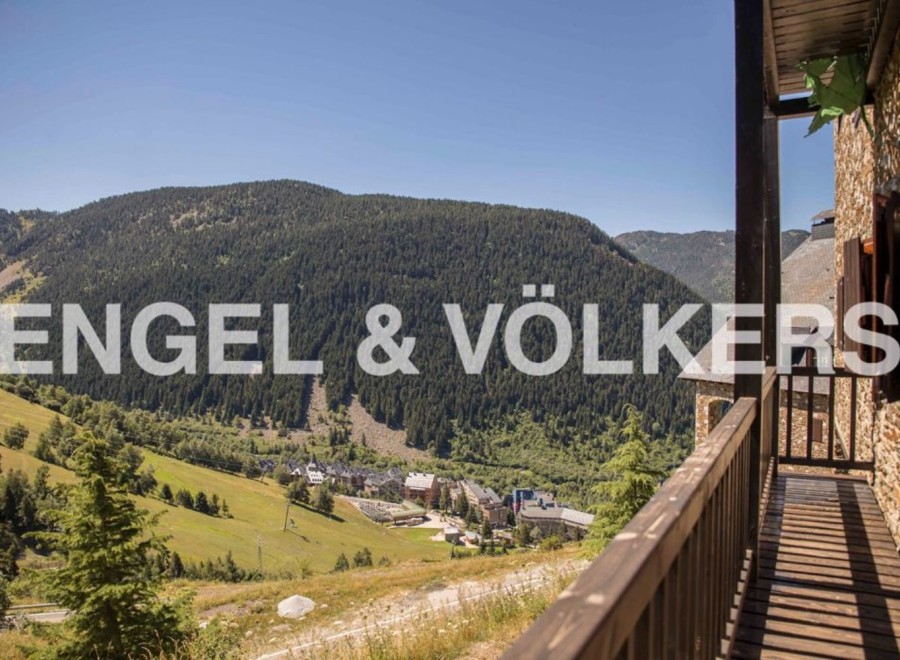 Mountain view home with wooden balcony and stone exterior.