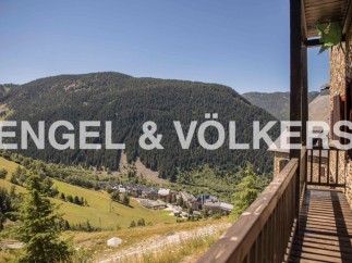 Mountain view home with wooden balcony and stone exterior.